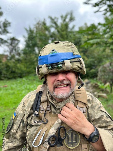 Portrait, Grimace of an elderly Ukrainian soldier in helmet with blue stripe, uniform of soldier of Ukrainian army