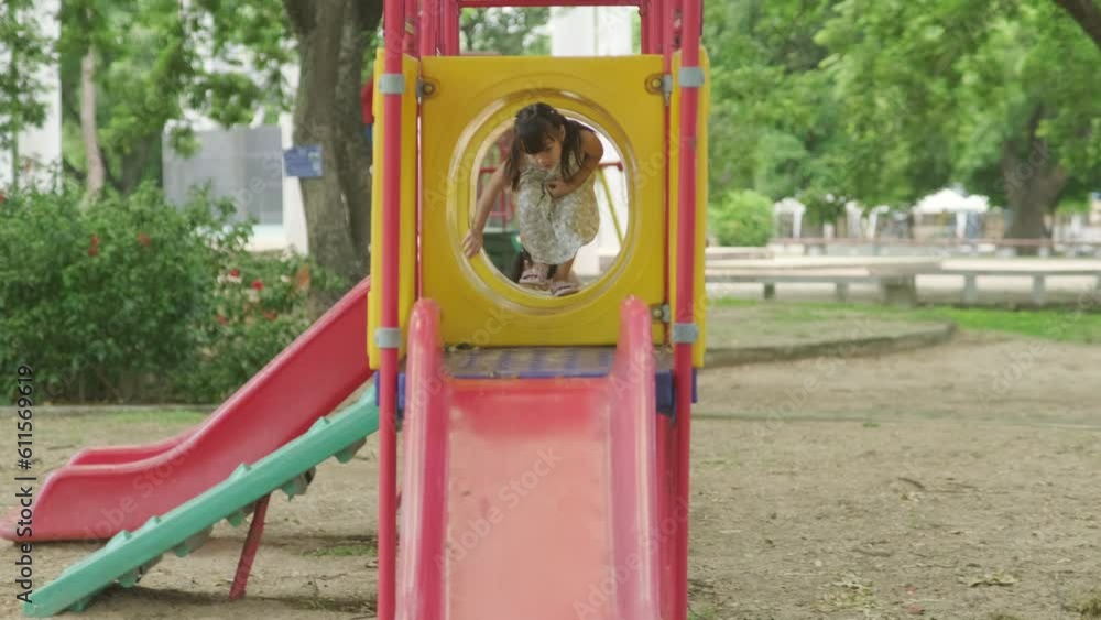 Happy girl having fun on colorful slides. Children playing slides at outdoor playground in park during summer vacation. Healthy activity. Happy girl having fun on colorful slides. Children playing slides at outdoor playground in park during summer vacation. Healthy activity.