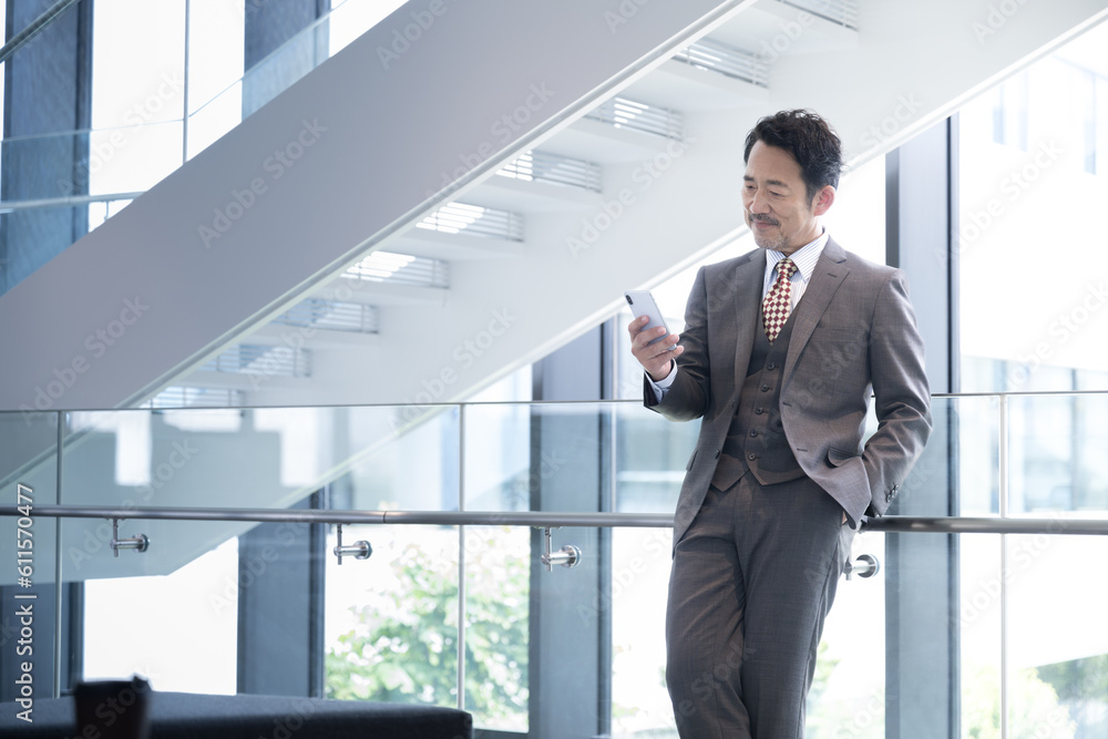スマホを見るハンサムな経営者や社長のイメージ 左にコピースペースあり スマホを見るハンサムな経営者や社長のイメージ 左にコピースペースあり