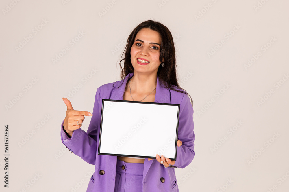 Beautiful young woman holding and pointing finger at empty blank white board, your text here concept. Smile Business woman portrait with blank white banner Beautiful young woman holding and pointing finger at empty blank white board, your text here concept. Smile Business woman portrait with blank white banner