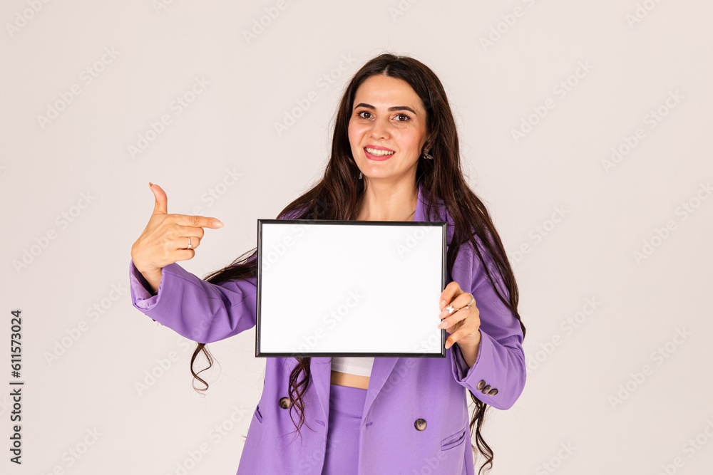 Beautiful young woman holding and pointing finger at empty blank white board, your text here concept. Smile Business woman portrait with blank white banner Beautiful young woman holding and pointing finger at empty blank white board, your text here concept. Smile Business woman portrait with blank white banner