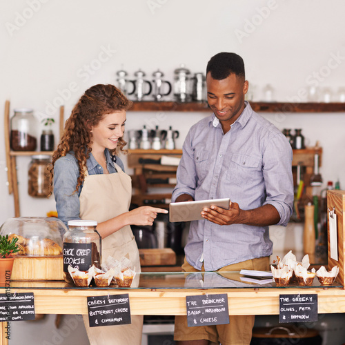 Employees, man and woman with a tablet, talking and update system with happiness, profit growth or store. Partners, manager or worker with technology, work schedule or collaboration with digital plan