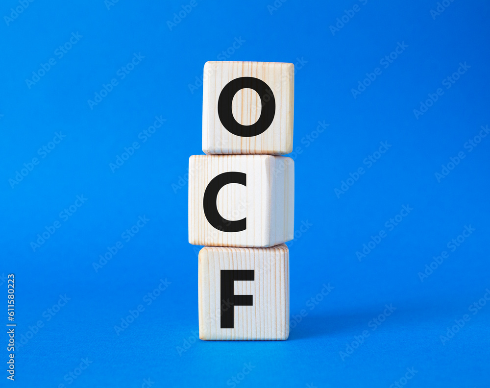 OCF - Operating Cash Flow symbol. Wooden cubes with words OCF. Beautiful blue background. Business and OCF concept. Copy space. OCF - Operating Cash Flow symbol. Wooden cubes with words OCF. Beautiful blue background. Business and OCF concept. Copy space.