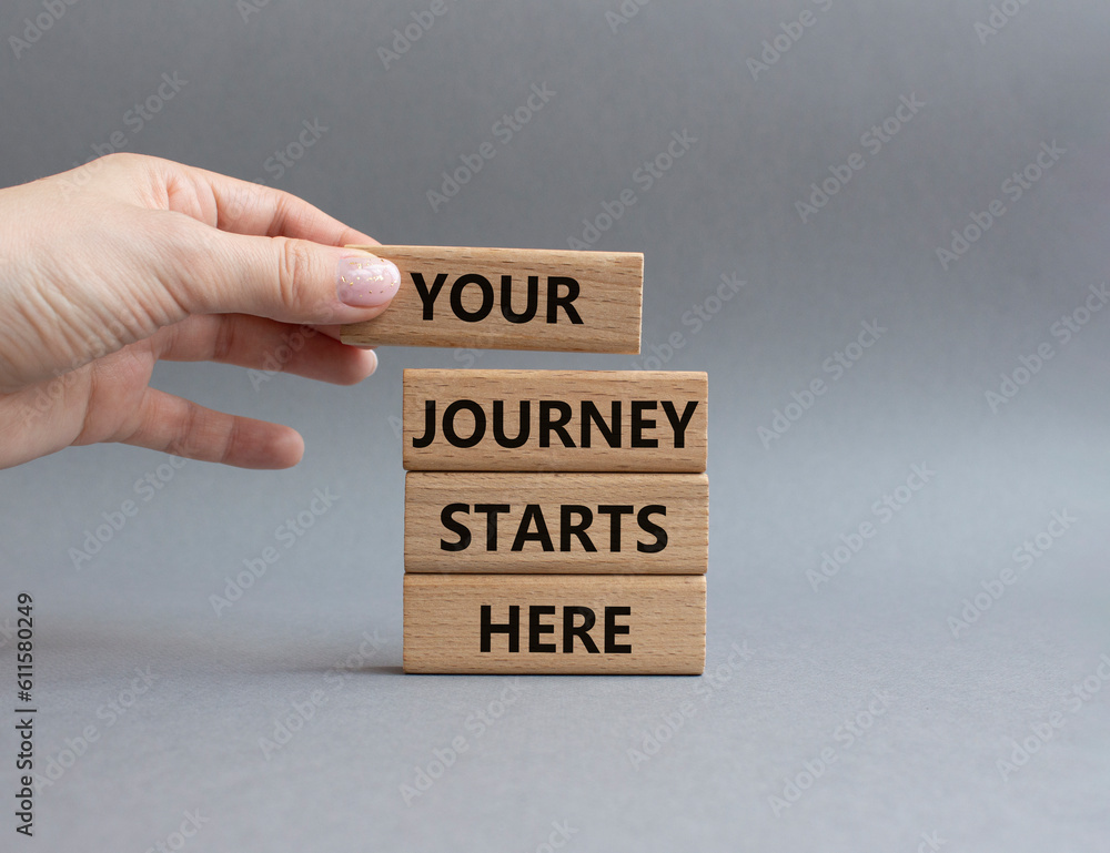 Your Journey starts here symbol. Concept word. Your Journey starts here on wooden blocks. Beautiful grey background. Businessman hand. Business and Your Journey starts here concept. Copy space Your Journey starts here symbol. Concept word. Your Journey starts here on wooden blocks. Beautiful grey background. Businessman hand. Business and Your Journey starts here concept. Copy space