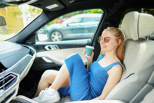 A young girl sit in the car drinks coffee and smile © Olga