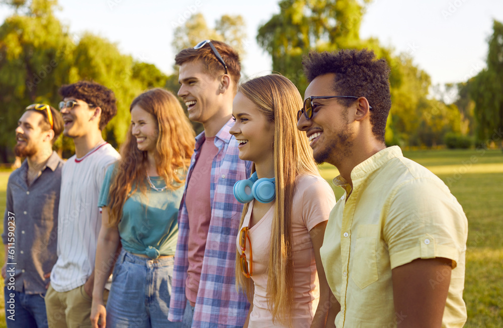 Diverse audience at an outdoor summer festival. Happy people enjoying a concert in nature. Company of young multiethnic male and female friends standing in the park and watching a live open-air show