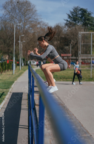 Sporty girls doing jumps on the bench in the park  on a beautiful sunny day