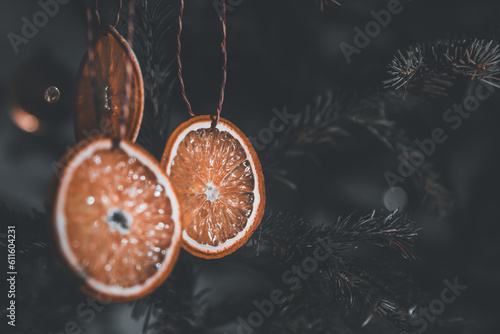 Dried orange decoration on christmas tree. Zero waste christmas concept. Christmas tree decorated with ornaments made of natural materials - slices of dried orange. Toned photo.