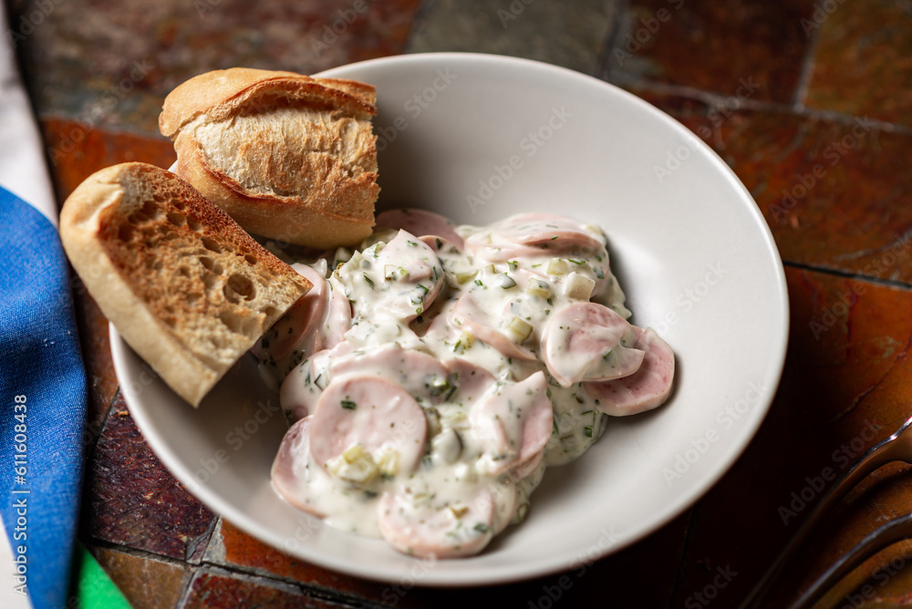 Sour cream and greens sausage salad on plate with bread. Simple salad on plate.