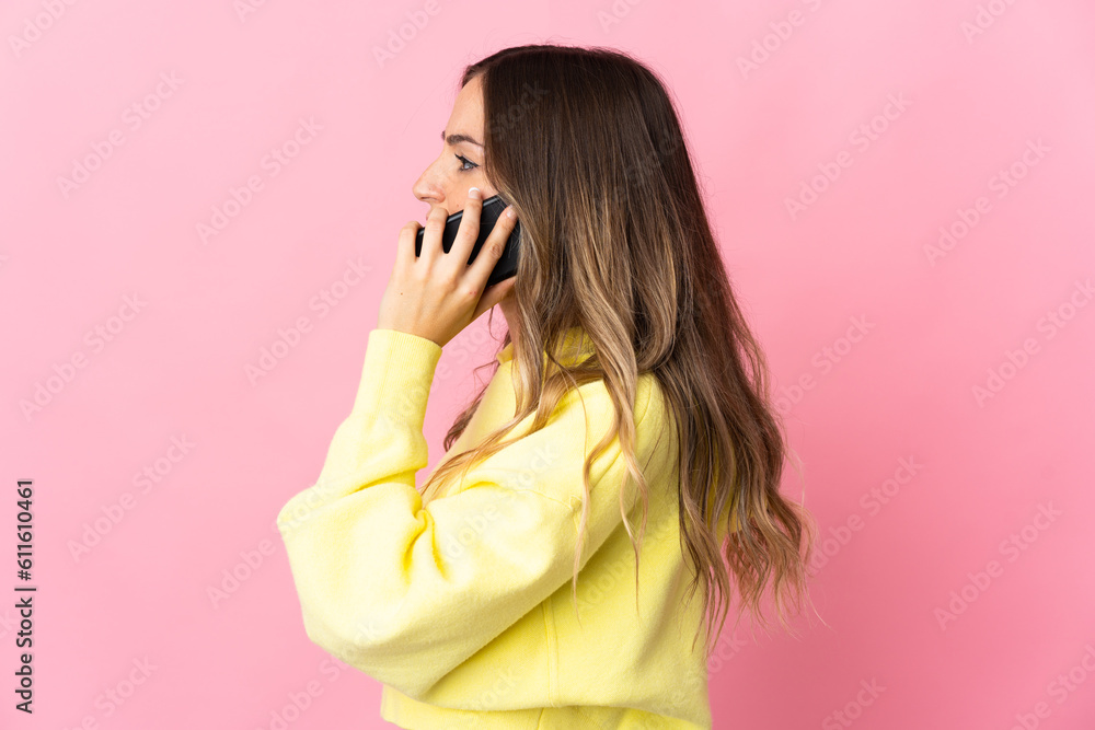 Young Romanian woman isolated on pink background keeping a conversation with the mobile phone with someone Young Romanian woman isolated on pink background keeping a conversation with the mobile phone with someone