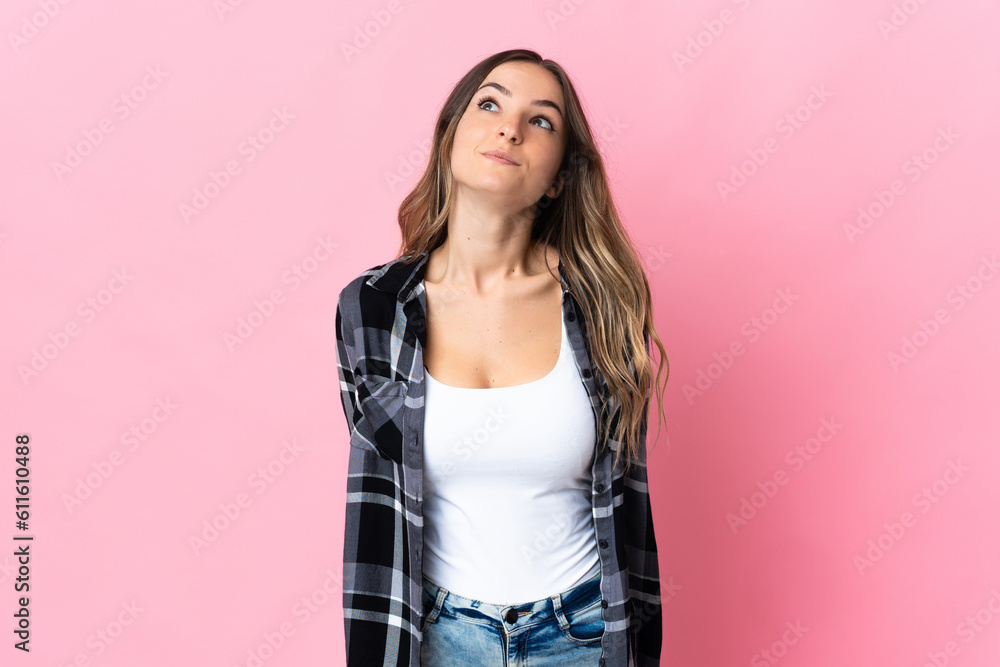 Young Romanian woman isolated on pink background and looking up Young Romanian woman isolated on pink background and looking up