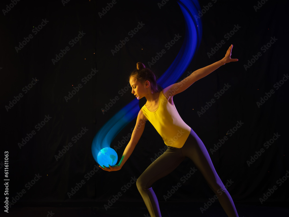 Girl gymnast doing beautiful exercise and catching ball in form and colors of Earth. Concept of saving Earth