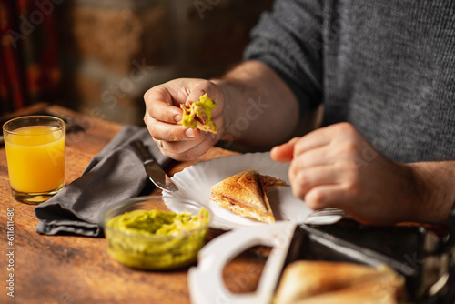 unrecognizable man eats toast with guacamole. Breakfast time. The man s hands are holding a toast.