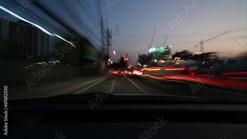 Time-lapse of freeway night traffic in downtown. Time-lapse of a fast night drive in a big city ends at a parking lot, car front view to road with vehicle streaks and street lights.