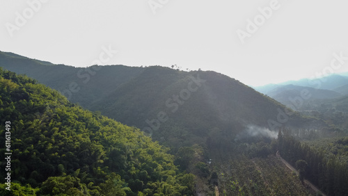 Idyllic landscape of mountains filled with green forests, grassy field and rolling hills.