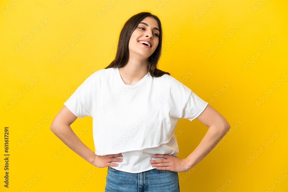 Young caucasian woman isolated on yellow background posing with arms at hip and smiling Young caucasian woman isolated on yellow background posing with arms at hip and smiling