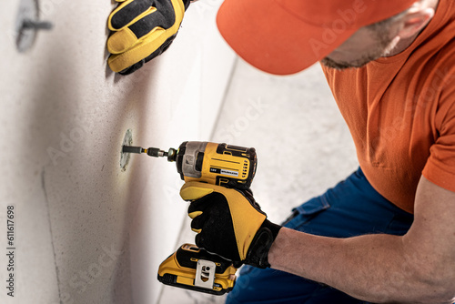 Bild auf Leinwand Screwing a dowel for thermal insulation using the aku impact wrench