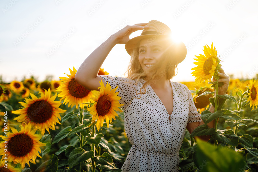 Beautiful woman posing in a field of sunflowers in a dress and hat.  Fashion, lifestyle, travel and vacations concept. - obrazy, fototapety, plakaty 