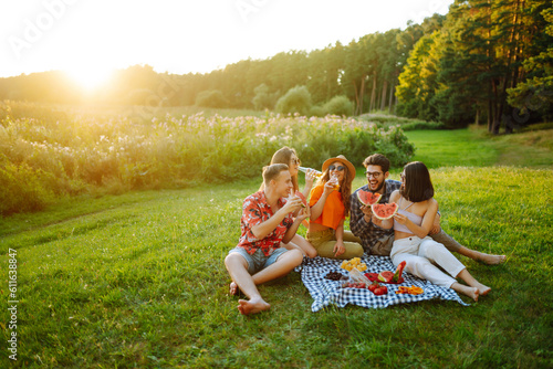 Group of young people have fun and drink beer in garden for picnic. Vacation, picnic, friendship or holliday concept.