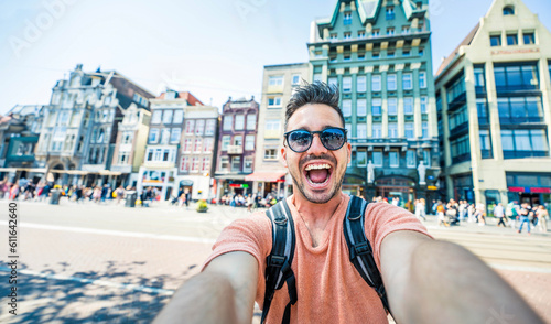 Happy tourist taking selfie picture in Amsterdam, Netherlands - Cheerful man using smart mobile phone device outside - Student traveler enjoying summer european vacation - Life style tourism concept