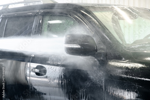 washing a black car with a jet of water under pressure