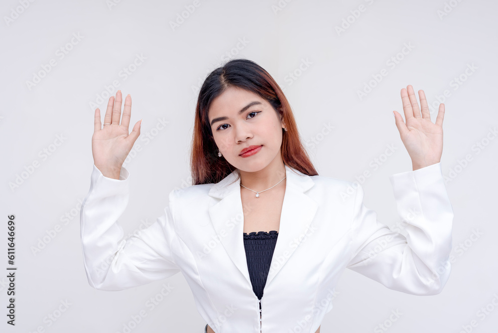 A composed and poker faced young woman with arms raised in surrender. Isolated on a white background. A composed and poker faced young woman with arms raised in surrender. Isolated on a white background.