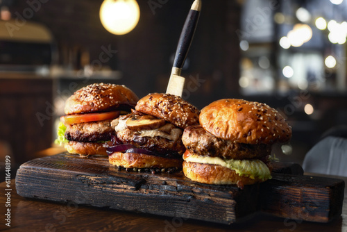 Close-up three different brutal burgers on wooden board in a burger joint