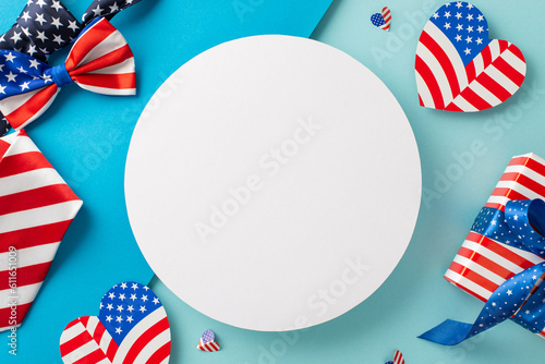 USA Unity Day imaginative greetings. Top view of symbolic items: tie, bow-tie, hearts featuring flag design, giftbox wrapped in thematic style, pastel blue backdrop with empty circle for text or ad
