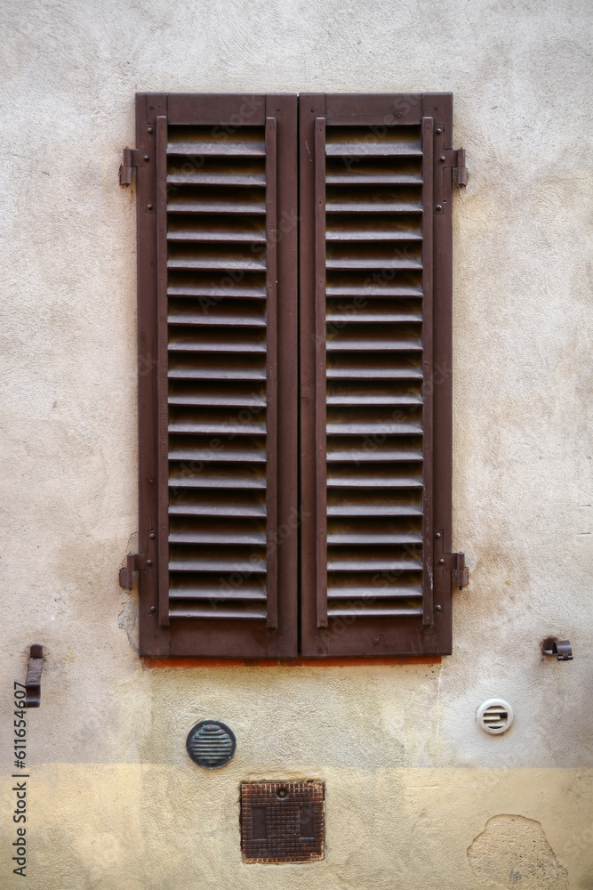 A frontal photo of a closed wooden window in Italy at a small home 