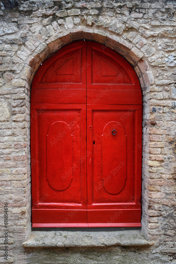 A photo of a red painted wooden door inside a stone facade in Italy A photo of a red painted wooden door inside a stone facade in Italy