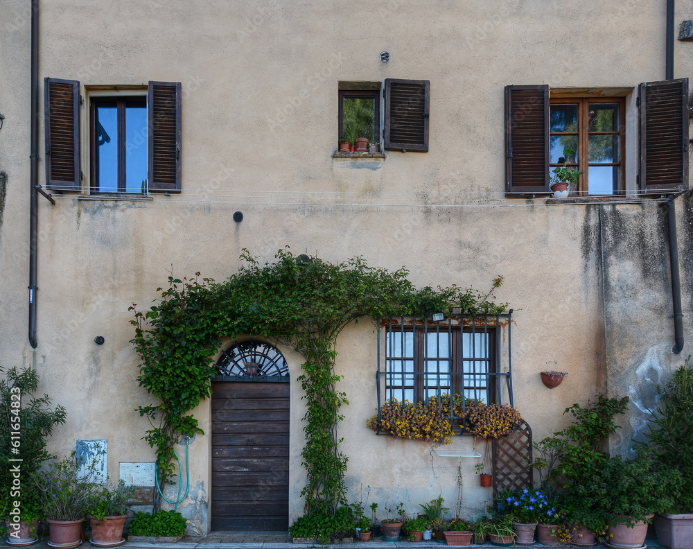 A frontal facade of an Italian house with many plants on it A frontal facade of an Italian house with many plants on it