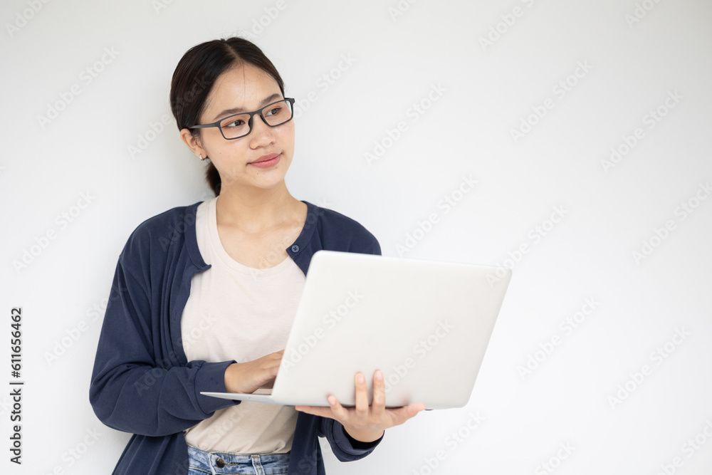 Asian teen girl with laptop computer standing on white wall thinking expression. Asian teen girl with laptop computer standing on white wall thinking expression.