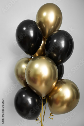 Gold chrome and black balloon, a bunch of balloons on the background of the wall.