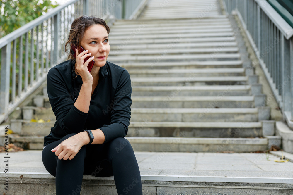 Fototapeta premium Young sporty woman talking on mobile phone