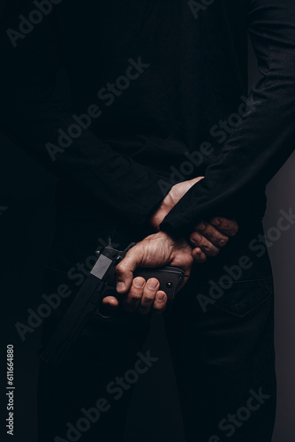 Close up of male hands holding aiming gun on a black background.