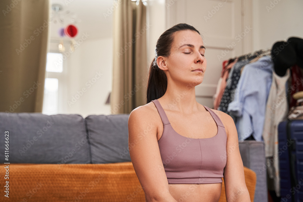 Brunette woman with closed eyes meditating at light living room Brunette woman with closed eyes meditating at light living room