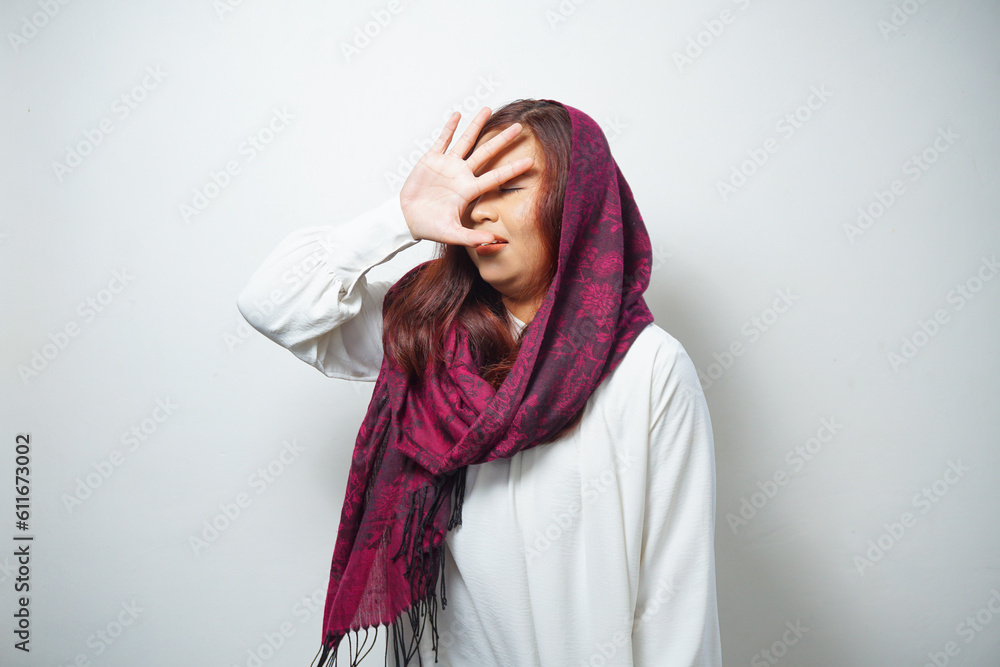 Young Asian Muslim woman isolated on white background, looks depressed, face covered by arms frightened and nervous. Young Asian Muslim woman isolated on white background, looks depressed, face covered by arms frightened and nervous.