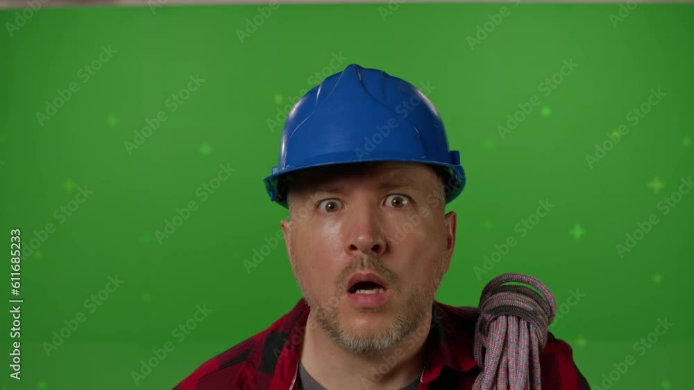 A male builder in professional ammunition and a construction helmet looking at the camera and being very surprised on a green background. copy space on chromakey A male builder in professional ammunition and a construction helmet looking at the camera and being very surprised on a green background. copy space on chromakey