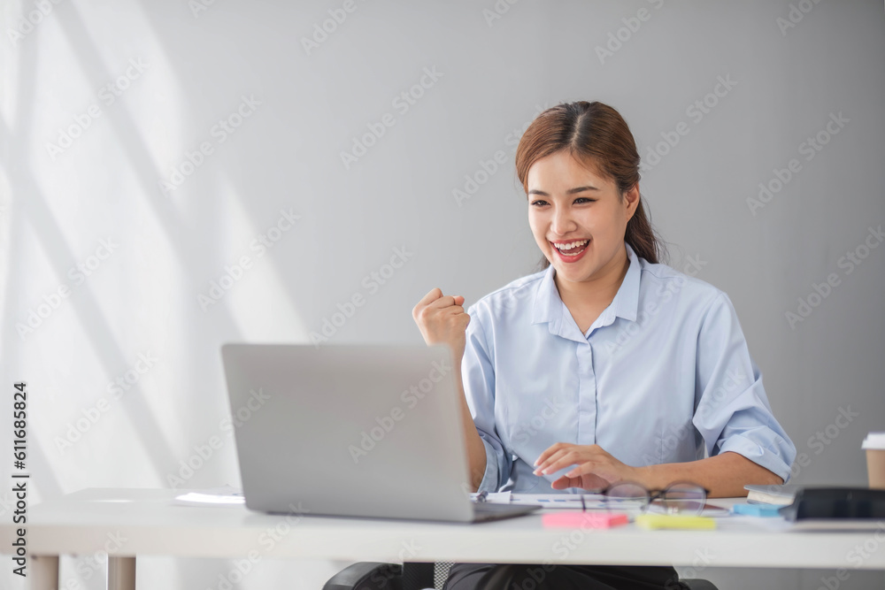 Asian businesswomen show joyful expression of success at work smiling happily with a laptop computer in a modern office. Asian businesswomen show joyful expression of success at work smiling happily with a laptop computer in a modern office.