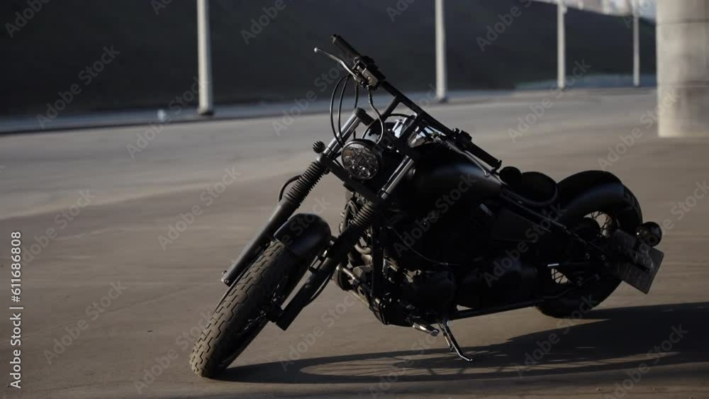 A black motorcycle is parked in an open parking lot. A black motorcycle is parked in an open parking lot.