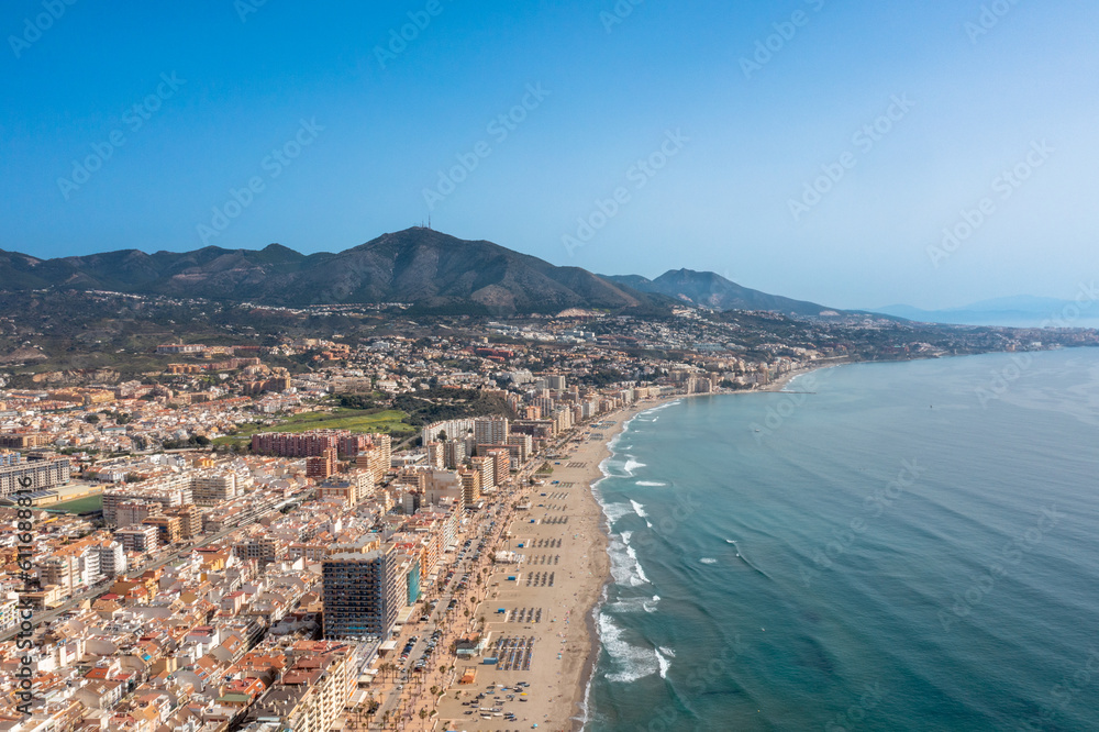 Aerial drone photo of the beautiful beach front of the coastal town of Fuengirola in Malaga Spain Costa Del Sol, showing the sandy beach, hotels and apartments with the mountains in the background