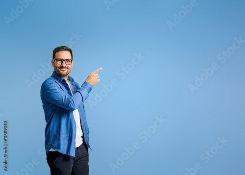 Fotografie Portrait of confident salesman pointing at product with copy space while standin