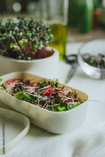 Salad in lunchbox with avocado, radish microgreen sprouts and tomato