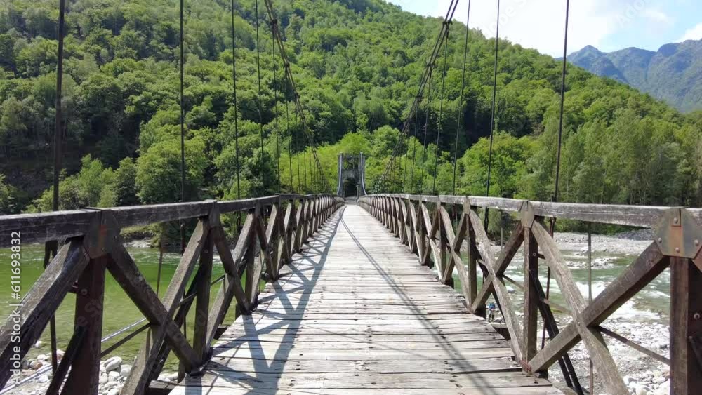 Drone flight over a wooden Tibetan suspended bridge that joins the river banks - view from the drone in Alagna Val Sesia Piedmont Alps mountains - travel concept journey in adventure natural trip Drone flight over a wooden Tibetan suspended bridge that joins the river banks - view from the drone in Alagna Val Sesia Piedmont Alps mountains - travel concept journey in adventure natural trip