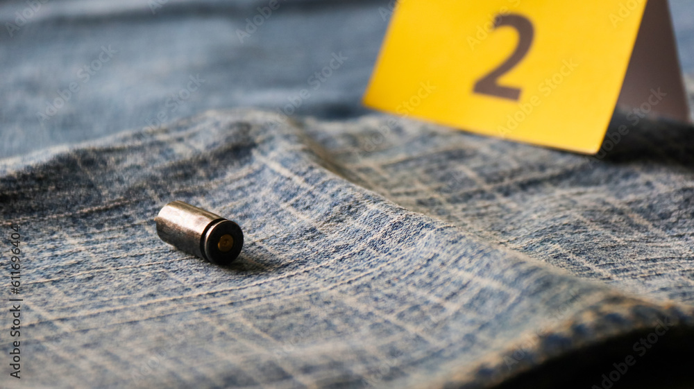 Pistol bullet shells on blur blue jeans and number two display in background, concept for criminal and investigation. soft focus Pistol bullet shells on blur blue jeans and number two display in background, concept for criminal and investigation. soft focus