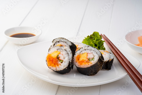 Maki sushi on white plate.Japanese sushi rolls with salmon, cucumber, shrimp eggs and Imitation Crab Stick with soy sauce dip and chopsticks on white wood background.