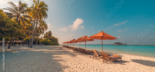 Fantastic panoramic view. Sandy shore soft sunrise sunlight over chairs umbrella and palm trees. Tropical island beach landscape exotic coast. Summer vacation, holiday. Relaxing sunrise leisure resort photo
