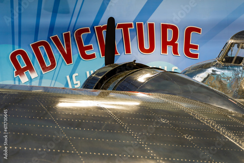 Left wing, engine, and cockpit of Electra passenger aircraft with adventure sign in the background photo