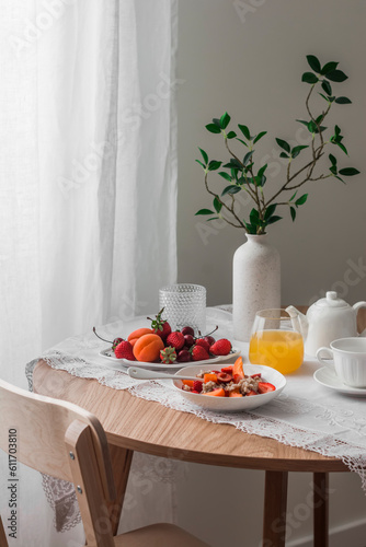Cozy breakfast served - porridge oatmeal with seasonal fruits and berries, orange juice, tea on a wooden round table