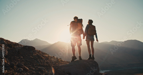 A silhouette of young adventurous couple watching the sunset standing on the top of mountain and holding hands. Traveling together. Happy and freedom concept © andreybiling